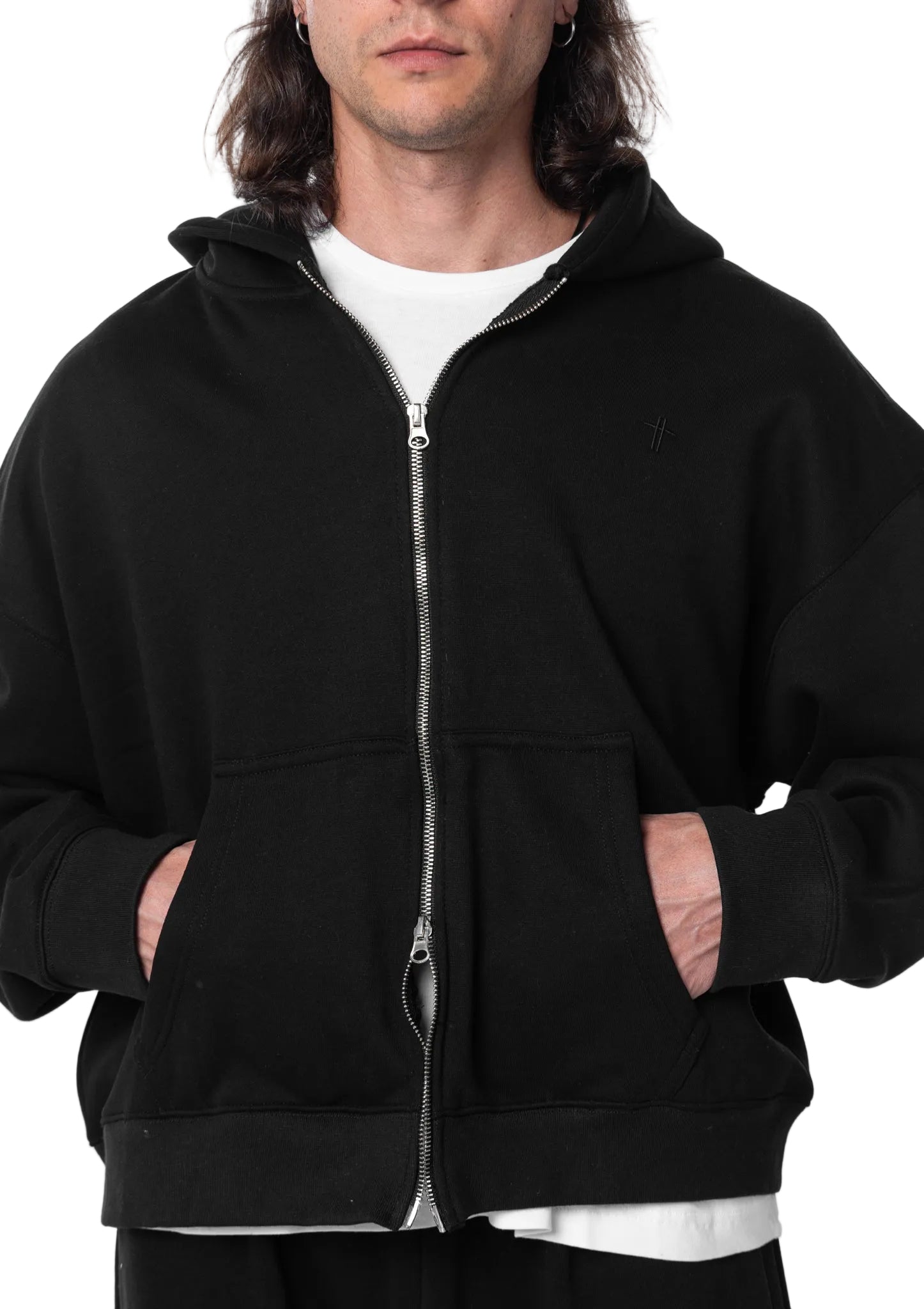 Person wearing a black hoodie with a white shirt underneath on a plain background