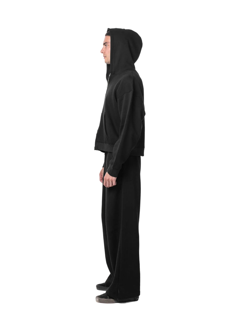 Person wearing a black hooded outfit on a white background